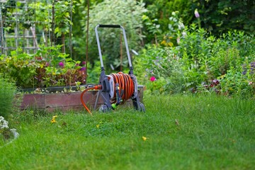 garden hose cart standing on green lawn with orange hose