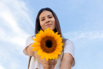 mujer joven, sonriendo y sosteniendo un girasol en un día soleado de primavera en un parque, enfoque selectivo, concepto de alegría, y belleza en primavera. paz, girasoles gigantes y amarillos.