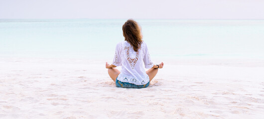 woman in meditation posture by the sea