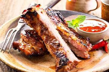 Barbecue veal spare ribs sliced with hot honey chili marinade served as close-up on a rustic design...