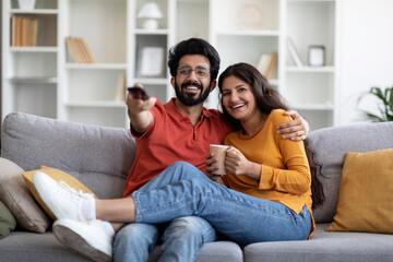 Portrait Of Happy Indian Spouses Watching Comedy Movie On Tv Together