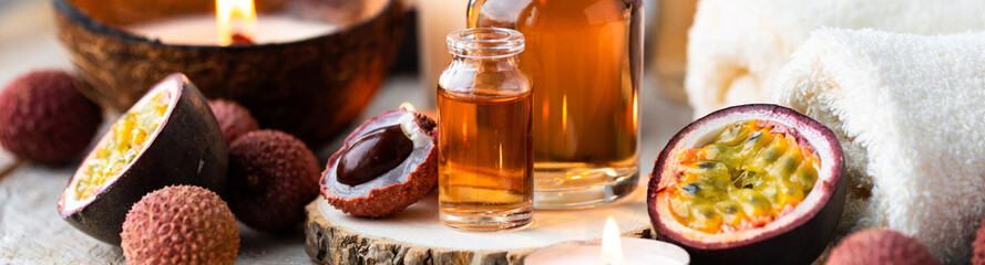 Glass bottles with pure organic essential litchi and passion fruit oil. Concept of natural ingredients for beauty treatment, skin care, massage. Exotic fruits extract and essence. Banner copy space
