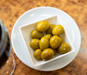 bowl contains large ripe shiny green olives with stone