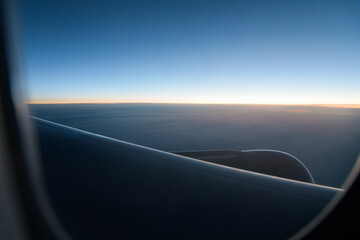 View through aircraft window at empty horizon at dawn on clear morning