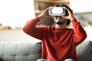 Excited Indian Man In VR Glasses Enjoying Virtual Reality Experience At Home