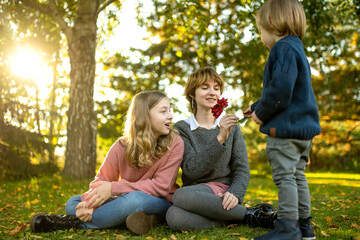Two big sisters and their toddler brother having fun outdoors. Two young girls with a toddler boy on autumn day. Children with large age gap. Big age difference between siblings.