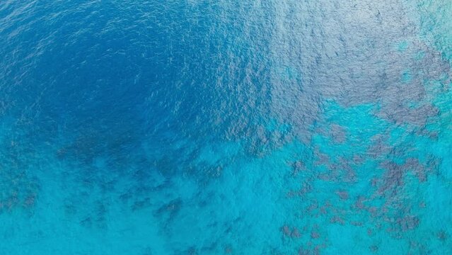 Aerial top down view of crystal sea surface with turquoise water, static shot