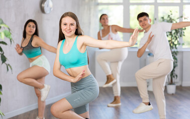 Fototapeta na wymiar Cheerful teen girl enjoying while training movements of modern group dance in choreography class ..