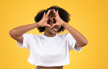 Happy millennial black woman in casual making heart sign with hands