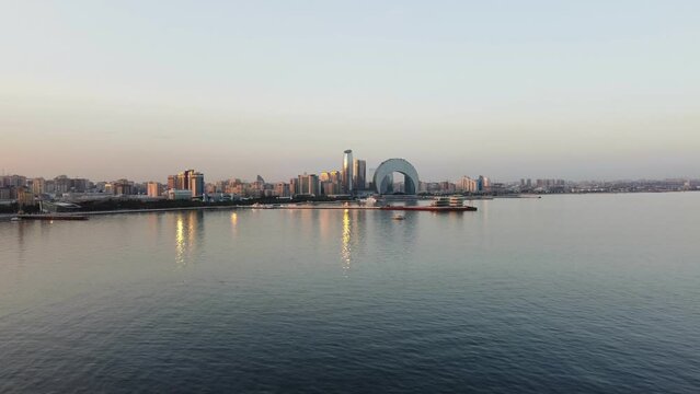 Baku, Azerbaijan - June 27, 2023: Drone footage taken at sunset, showing the magnificent Crescent Hotel and surrounding skyscrapers, with a backdrop of the stunning Baku skyline.