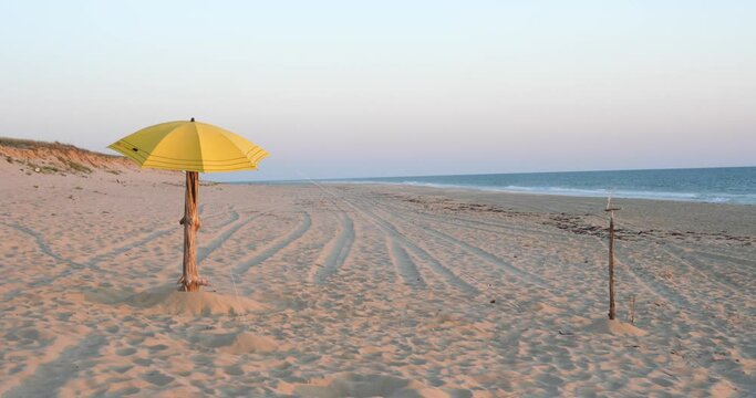 A yellow beach umbrella on the beach of Cap Ferret at dusk. June 2023, France.