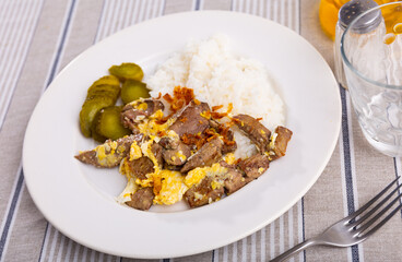 Plate with omelet fried with rabbit liver served with side dish of white rice and slices of savory homemade pickles