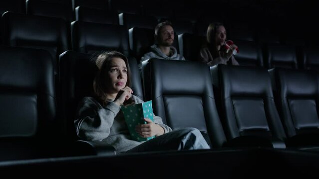 A woman with emotions watching a movie at the cinema. A spectator at the premiere of the film. Exciting moments of the plot