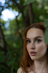 Naklejka premium very beautiful freckled white woman with long red hair in a garden
