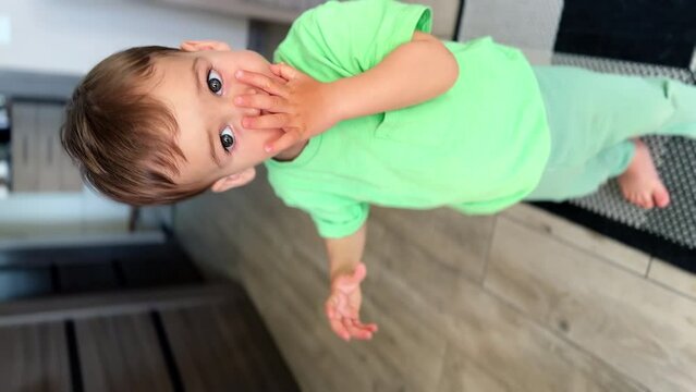 A parent's hand giving a snack to a little baby. Kid puts it quickly into mouth, smiles and runs away. Vertical screen.