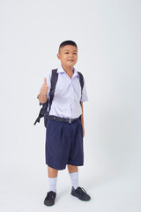 A young Asian cute boy standing in a Thai school uniform with a backpack bag and book on a white background banner