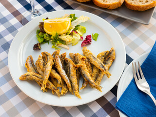 Delicious fried anchovy with lettuce and lemon on white plate