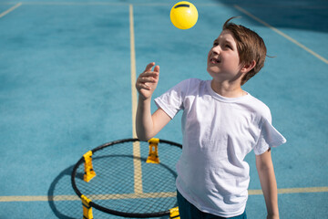 child playing sports game spikeball, spikeball. the boy is hitting the yellow ball in a miniature...