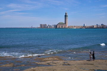 Muslim couple in traditional clothes at the celebration of Eid al-Fitr. The view point on the Hassan II Mosque with a minaret that rises above the Atlantic Ocean, Casablanca, Morocco