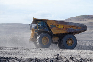 old rusty yellow mining truck on job, transporting coal