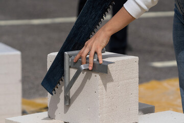 Woman cuts aerated concrete with a masonry saw.