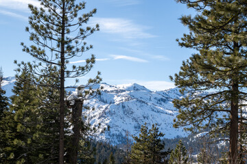 View of the mountains of Squaw Valley at a distance, on a mostly sunny blue sky day, from between...