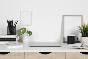 Cozy workspace with laptop, houseplants and stationery on wooden desk at home