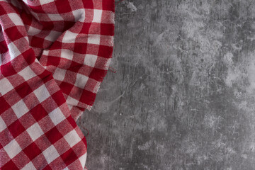 Fototapeta premium Concrete table with red and white checkered tablecloth, seen from above.