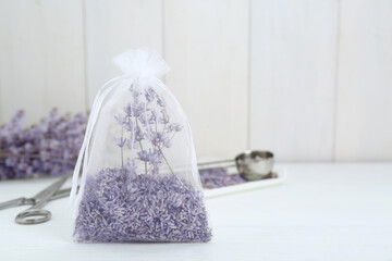 Scented sachet with dried lavender flowers on white table, space for text