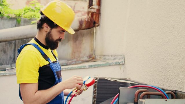 Expert mechanic calibrating pressure measurement device during comissioned air conditioner troubleshooting. Experienced repairman reading vacuum pressure of condenser liquids and gases