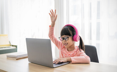 Portrait of Asian girl rise hand computer to learn online live lesson in elementary school. Student...