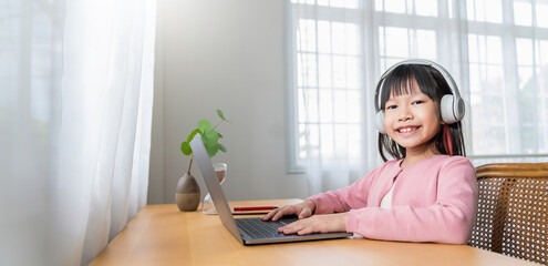 Portrait of Asian girl using computer to learn online live lessons in elementary school. Student boy studying in primary Children with gadgets at home. Education knowledge, technology internet network
