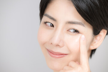 美容などに使いやすい睫毛や目元を指さすアジア系（日本人）女性のアップ