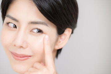 Close-up of an Asian (Japanese) woman pointing at her eyelashes and eyes, easy to use for beauty and other purposes.