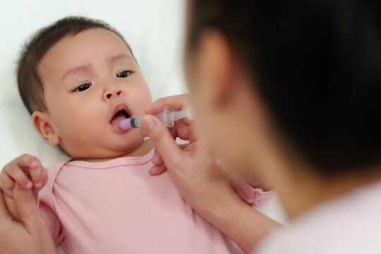 Mother Feeding A Medicine To Sick Infant Baby With Syringe