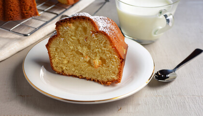 Slice of yogurt bundt cake served with a cup of coffee with milk
