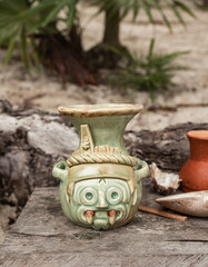 Green Maya handcraft ceramic in a tropical sandy garden surrounded by green vegetation in Tulum on a sunny day