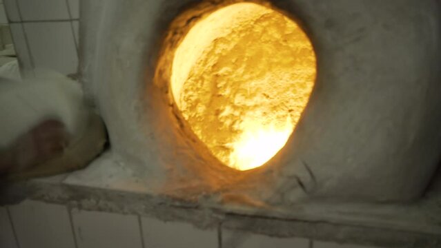An artisan baker puts chapatis cakes in a traditional oven, in Bahrain