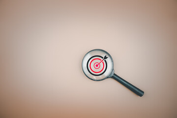 Target board inside magnifier glass for focus business objective with copy space. Idea of leading to a goal learn to plan, achieve investment strategy success and improve performance.