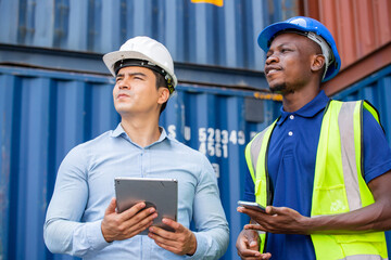 Logistic foreman discussing business work with African contractor worker at container warehouse or...