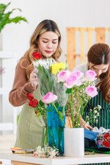 Asian professional successful female florist designer flower shop owner entrepreneur and colleague employee helping decorating flower bouquet in vase in floral garden store studio.
