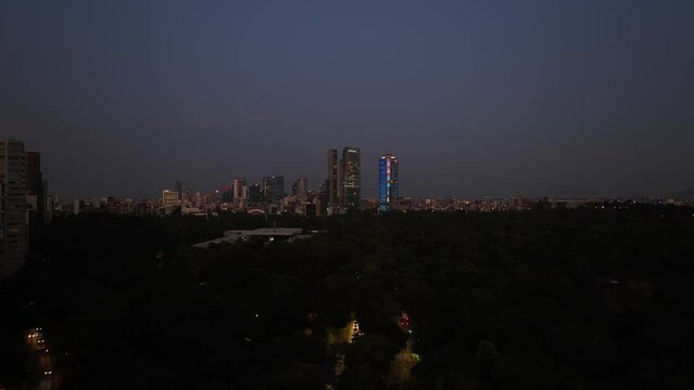 Aerial view over the Chapultepec park with downtown skyscrapers in the background, dusk in Mexico city