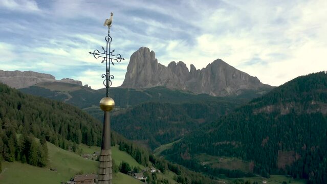 Aerial drone shot of a catholic church top cross with the Italian dolomites alps mountains in the background 01