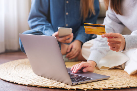 Closeup image of a young couple women using laptop computer and credit card for online shopping at home