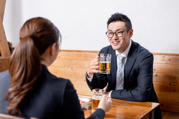 居酒屋でお酒・ビールを飲むビジネスマンと女性
