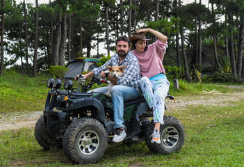 Portrait of young married couple sitting on a quad bike in the forest