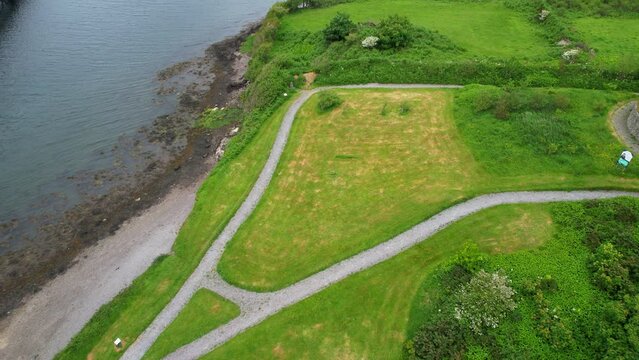 Small park with pathways and vibrant green grass by the shore of Valentia River. Cahersiveen, Ireland