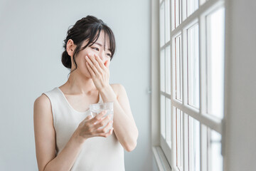 薬を飲む頭痛・体調不良のアジア人女性
