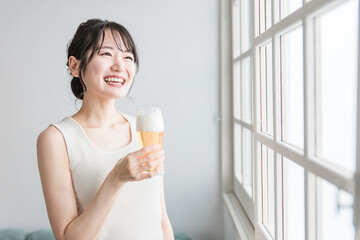 家でビールを昼飲みするアジア人女性（ビールグラス）
