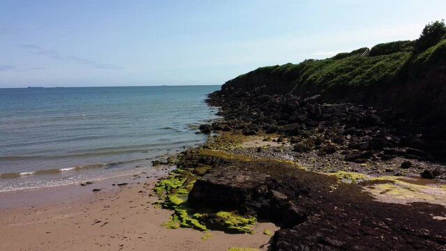Aerial view Traeth Lligwy Jurassic rocky weathered rugged Anglesey coastal seascape, push in low
